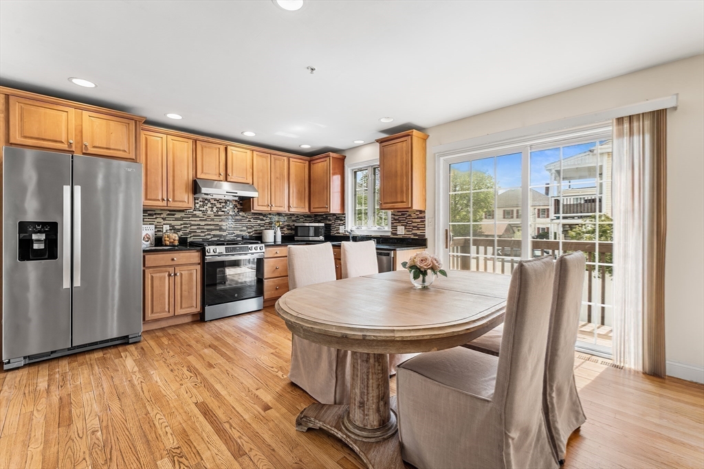 30 Russell Street, Unit 5 Waltham, MA 02453 - Photo 11 of 26 a kitchen with stainless steel appliances granite countertop a stove a refrigerator a kitchen island a table and chairs in it