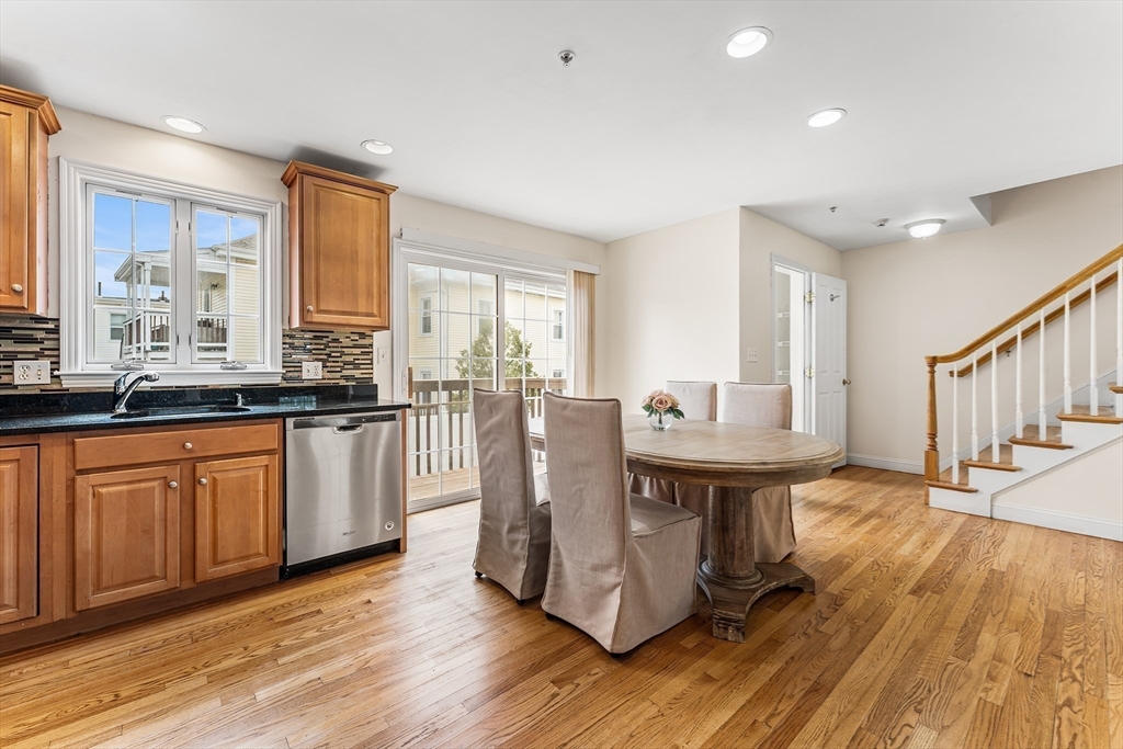 30 Russell Street, Unit 5 Waltham, MA 02453 - Photo 9 of 26 a kitchen with stainless steel appliances granite countertop a stove a sink dishwasher and a dining table with wooden cabinet
