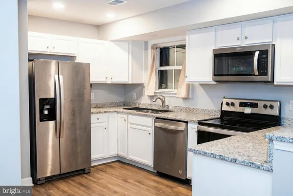 a kitchen with stainless steel appliances granite countertop a refrigerator stove top oven and sink