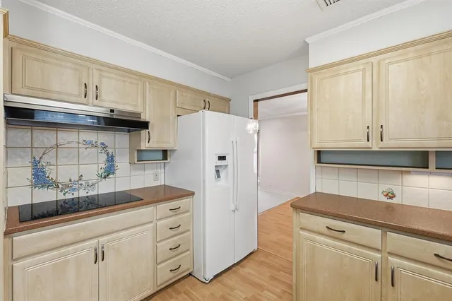 a kitchen with granite countertop white cabinets and refrigerator
