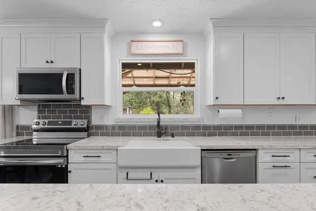 a open kitchen with stainless steel appliances granite countertop a stove top oven a sink dishwasher and a refrigerator with wooden floor