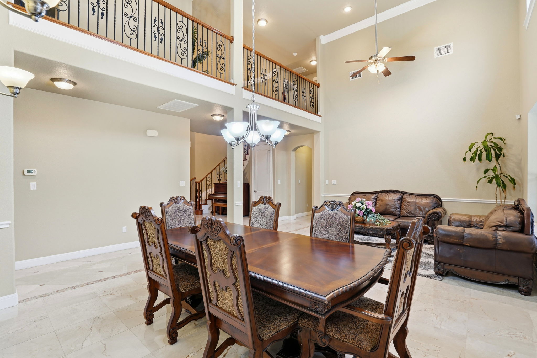 222 Vailco Lane Austin, TX 78738 - Photo 22 of 39 Open concept living area featuring high ceilings, a second-story interior balcony with wrought iron railing, and light-toned tile flooring