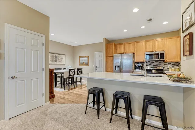 a kitchen with stainless steel appliances granite countertop a stove a sink a refrigerator with white cabinets a dining table and chairs