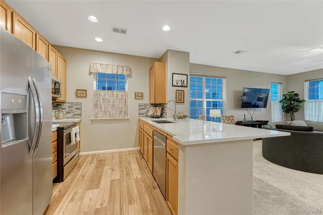 a kitchen with stainless steel appliances granite countertop a refrigerator a sink dishwasher a oven with white cabinets and wooden floor