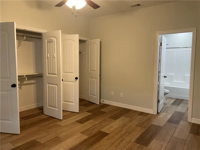 an empty room with wooden floor a sink and a mirror