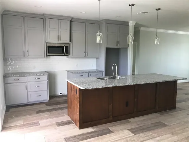 a kitchen with stainless steel appliances granite countertop a sink and a stove top oven with wooden floor