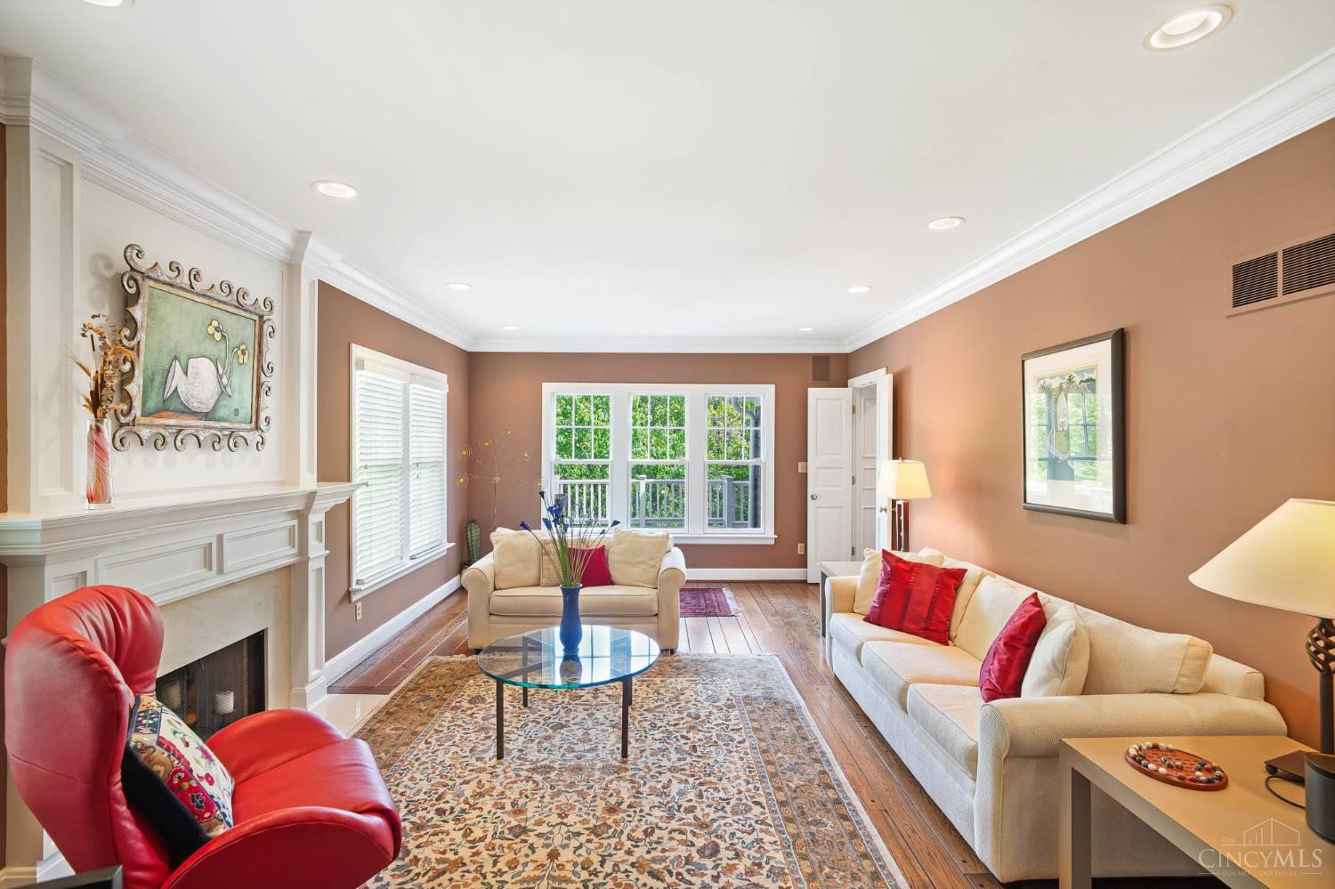 2780 Walsh Road Cincinnati, OH 45208 - Photo 19 of 68 The inviting formal living room balances classic elegance with warmth and comfort. Rich hardwood floors, crown molding and a beautifully detailed fireplace create a timeless backdrop, while expansive windows fill the space with natural light. Generously scaled and ideal for entertaining, the room offers multiple seating areas with serene treetop views.