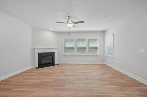 a view of an empty room with wooden floor fireplace and a window