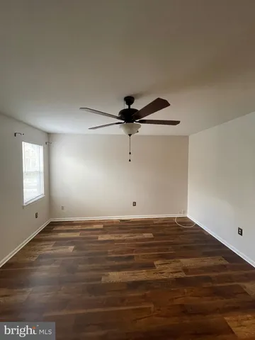 a view of an empty room with window and a ceiling fan