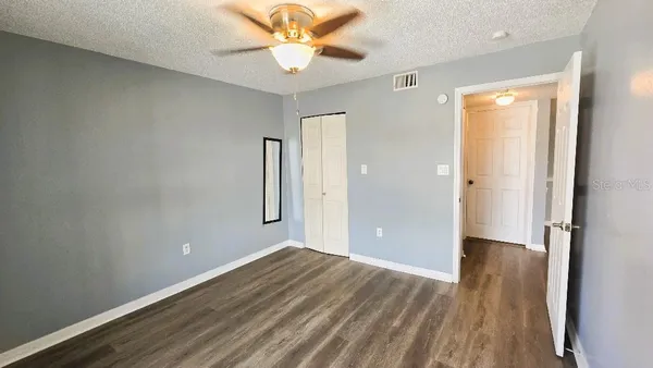 an empty room with wooden floor and a ceiling fan