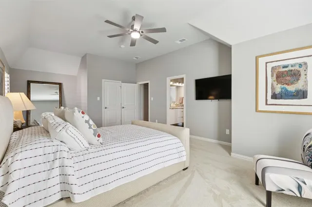 a spacious bedroom with a bed and a flat screen tv