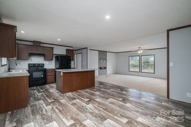 a large kitchen with stainless steel appliances kitchen island granite countertop a stove a sink a refrigerator and a cabinets