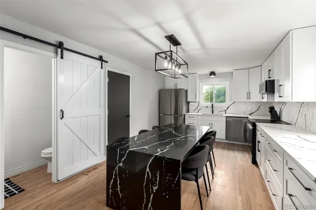 a kitchen with kitchen island a counter top space a sink stainless steel appliances and cabinets