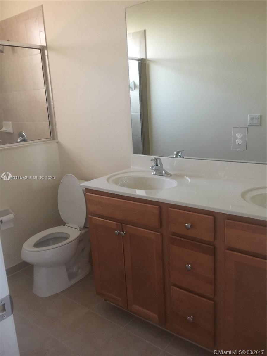 17059 Southwest 96th Street Miami, FL 33196 - Photo 16 of 22 a bathroom with a granite countertop toilet sink and mirror