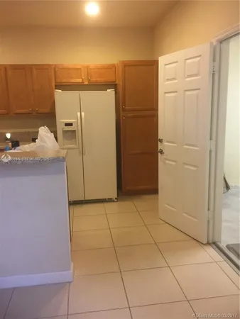 a view of a refrigerator in kitchen and an empty room