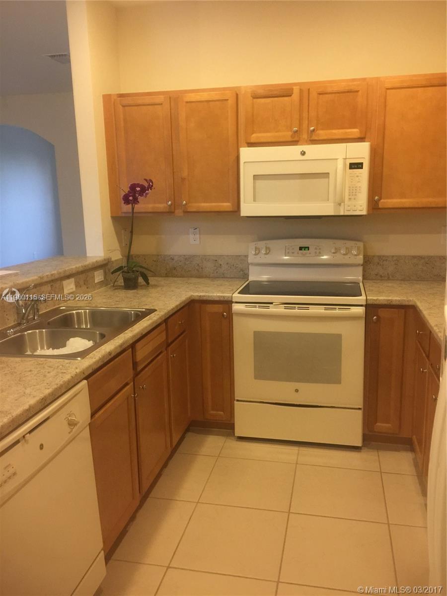 17059 Southwest 96th Street Miami, FL 33196 - Photo 7 of 22 a kitchen with a stove top oven sink and cabinets