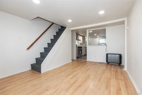 a view of an empty room with wooden floor and stairs
