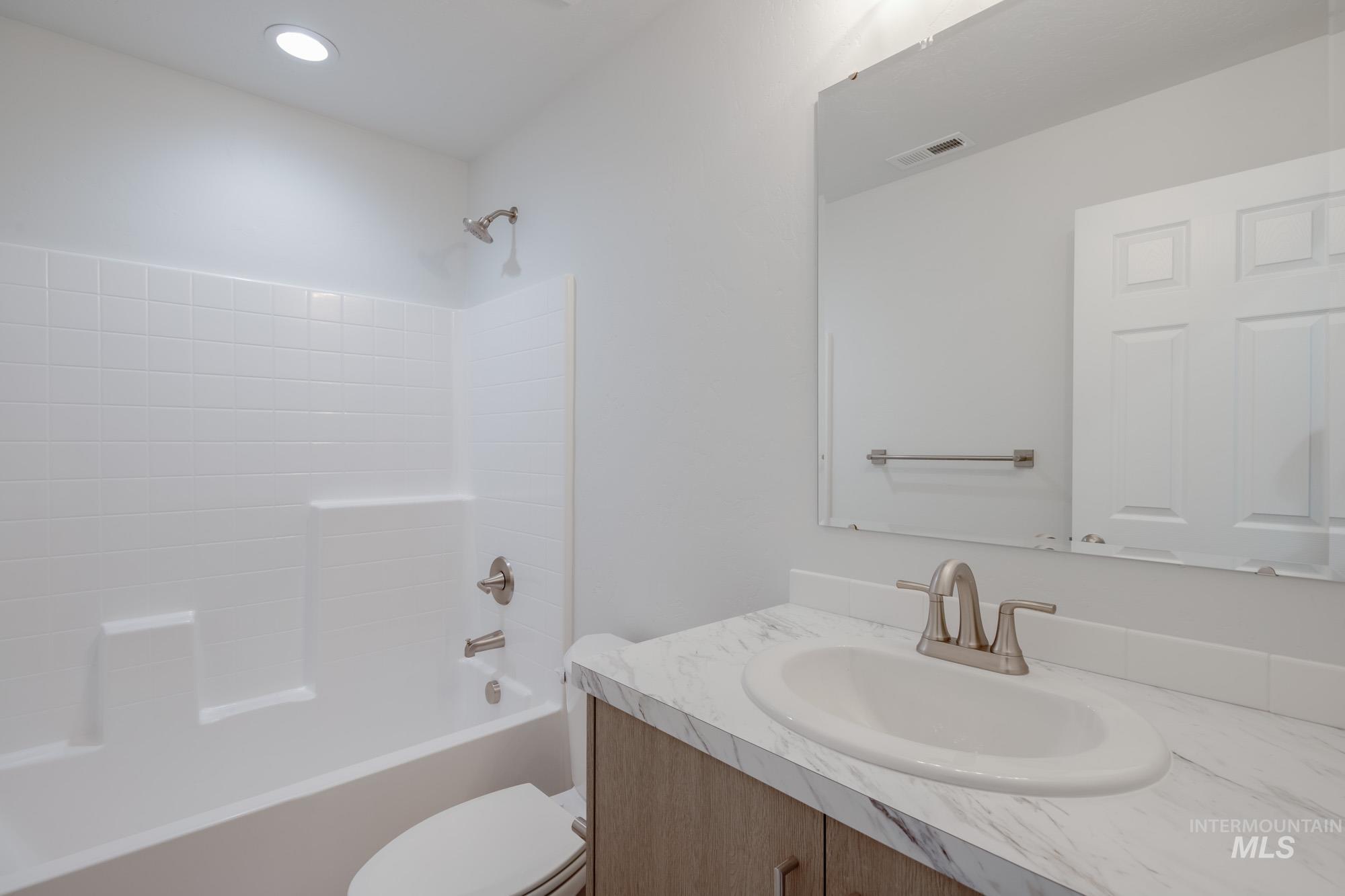 14092 Shiny Spruce Street Caldwell, ID 83607 - Photo 17 of 22 Bathroom featuring a shower-tub combination with white subway tile surround, recessed lighting, a vanity with a white countertop and integrated sink, and brushed nickel fixtures