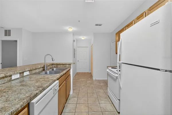a kitchen with granite countertop a refrigerator and a stove top oven