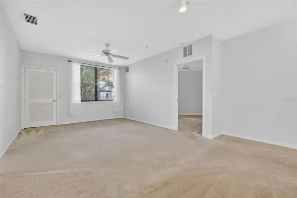 an empty room with a window and a ceiling fan