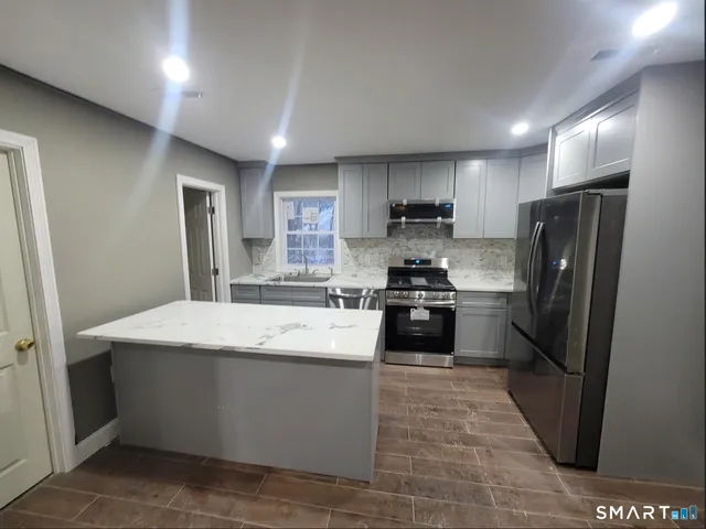 a kitchen with stainless steel appliances granite countertop a refrigerator a stove a sink and a oven