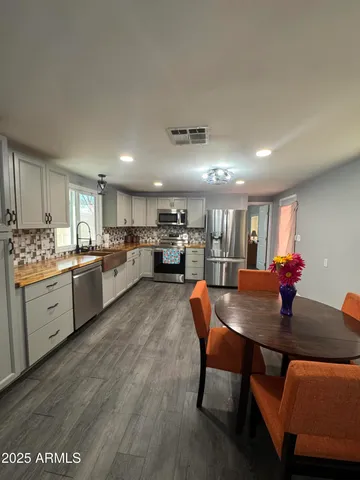 a open dining room with stainless steel appliances kitchen island granite countertop a table chairs and a refrigerator