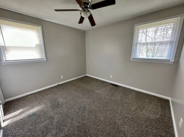 an empty room with a ceiling fan and carpet