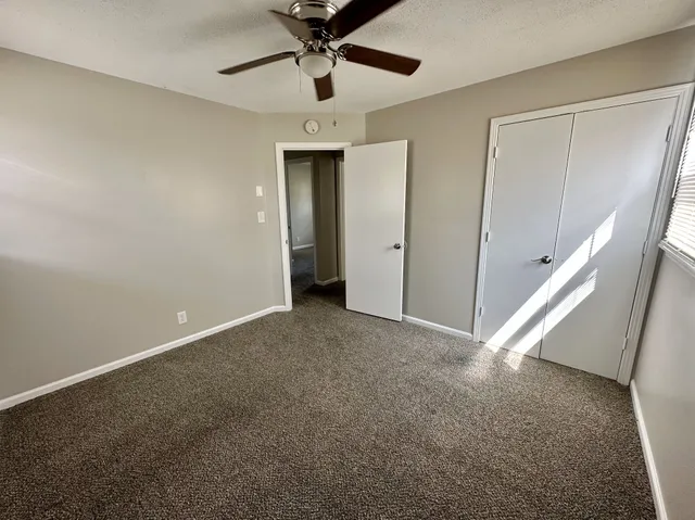 an empty room with windows and fan