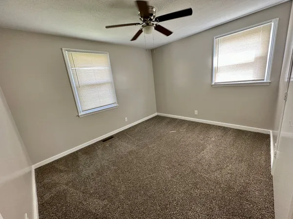 an empty room with a ceiling fan and carpet