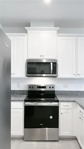 a kitchen with granite countertop white cabinets and black appliances