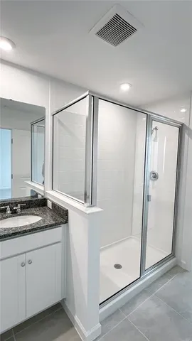 a bathroom with a granite countertop sink mirror and shower