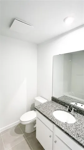 a bathroom with a granite countertop toilet and a sink