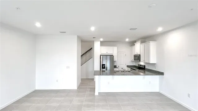 a view of kitchen with kitchen island a sink wooden floor and a refrigerator