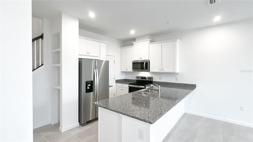 4268 Sadler Road Apopka, FL 32712 - Photo 7 of 28 a kitchen with stainless steel appliances granite countertop a refrigerator a stove and a sink