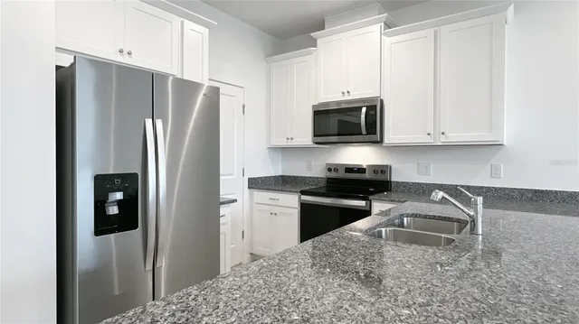 a kitchen with granite countertop a refrigerator stove and microwave