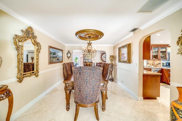 a large kitchen with stainless steel appliances granite countertop a large kitchen island a stove a sink a dining table and chairs with the front of the kitchen