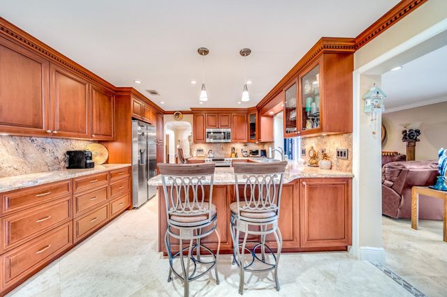 a kitchen with kitchen island granite countertop a sink and wooden cabinets