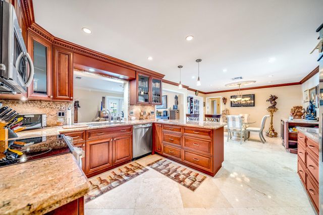 a kitchen with stainless steel appliances kitchen island granite countertop dining table chairs and a refrigerator