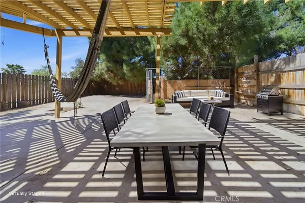 a view of a patio with a table and chairs under an umbrella with wooden floor and fence