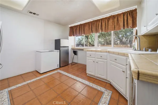 a kitchen with white cabinets and window
