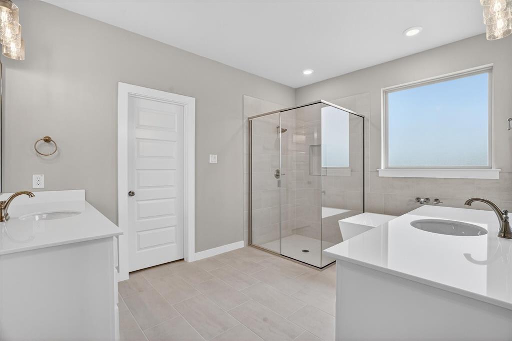 504 Clifton Court Springtown, TX 76082 - Photo 30 of 36 Bathroom featuring dual vanities with white countertops, a frameless glass shower enclosure, a built-in bathtub, and light tile flooring
