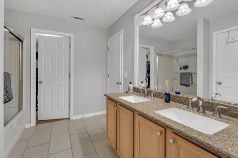 a bathroom with a granite countertop sink a large mirror and a shower