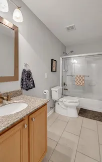 a bathroom with a granite countertop sink a toilet a mirror and bathtub