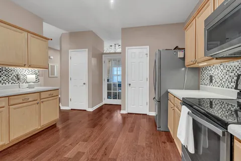 a kitchen with stainless steel appliances granite countertop a refrigerator a stove a sink and white cabinets with wooden floor