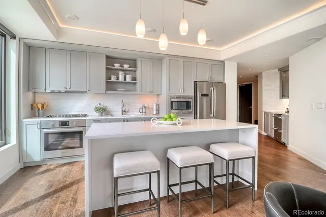 a kitchen with stainless steel appliances granite countertop a table chairs refrigerator and sink