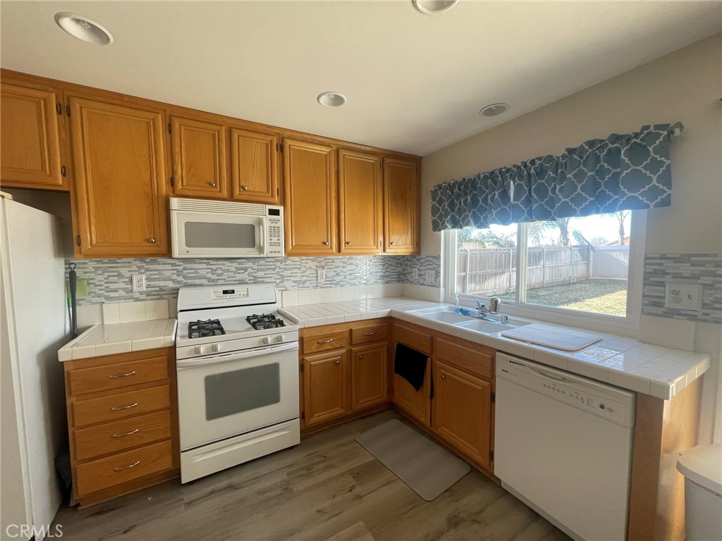 965 Hardwick Avenue Beaumont, CA 92223 - Photo 6 of 19 a kitchen with stainless steel appliances granite countertop a sink and cabinets with wooden floors