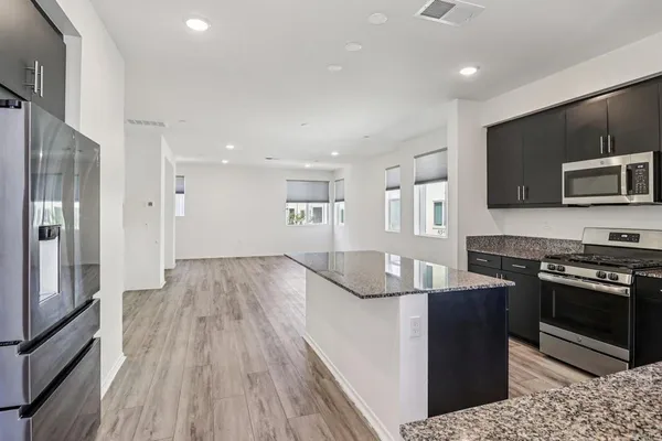 a kitchen with kitchen island granite countertop a sink stove and refrigerator