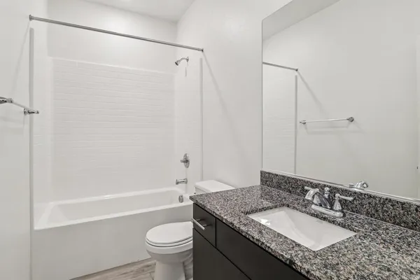 a bathroom with a granite countertop sink a toilet and shower