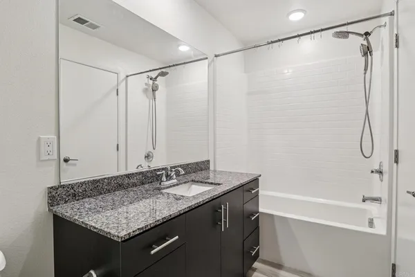 a bathroom with a granite countertop sink shower and a mirror