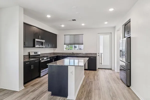 a kitchen with stainless steel appliances granite countertop wooden cabinets a refrigerator a stove a sink and a microwave